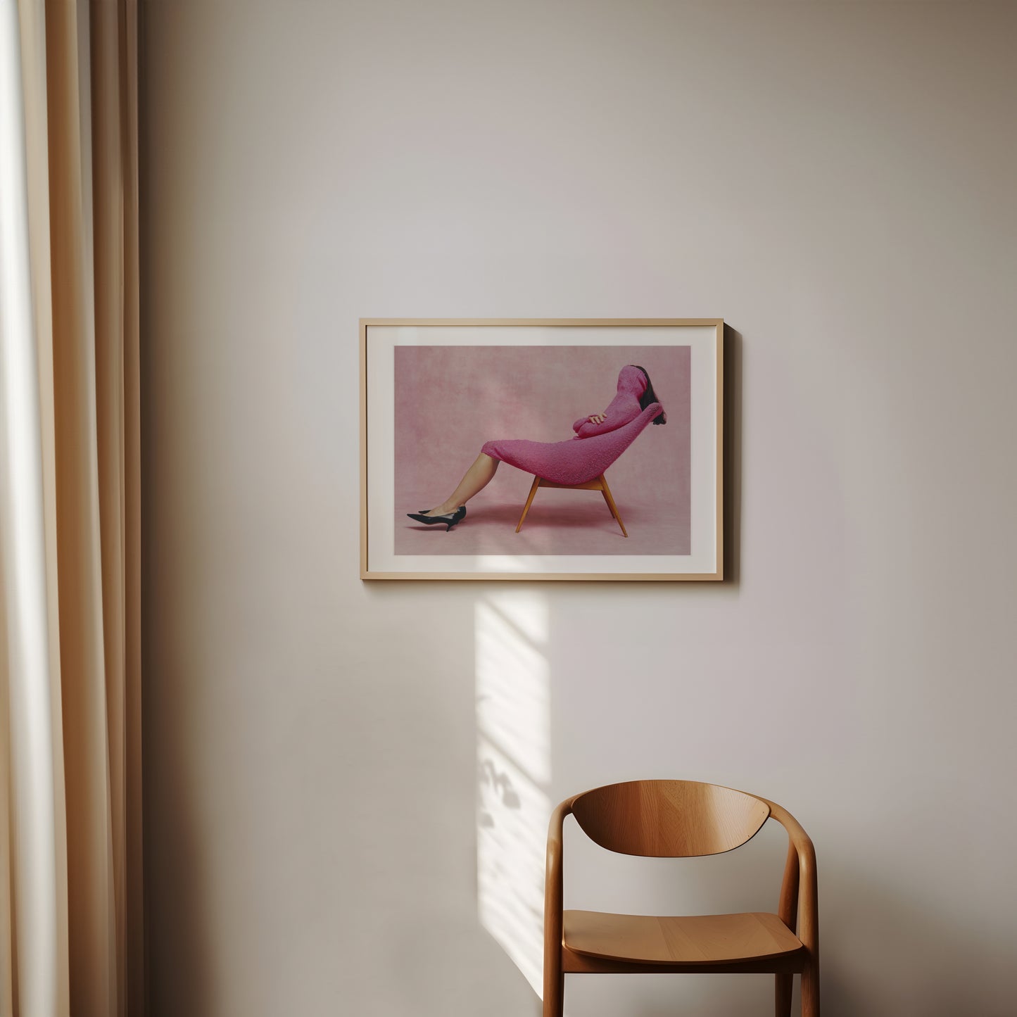 Wooden framed of a poster with a woman with pink dress hanged on a wall of sunlit room